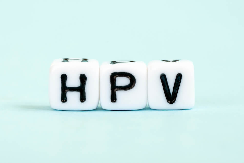 קוביות לבנות עם הכיתוב HPV על רקע תכלת – המחשה לנגיף הפפילומה האנושי ולתסמיני קונדילומה